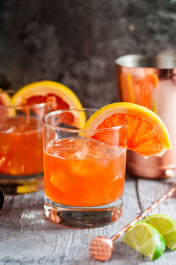 The Campanella - a Paloma Cocktail Variation - old fashioned glass of orange cocktail, another in the background, garnished with half a grapefruit wheel